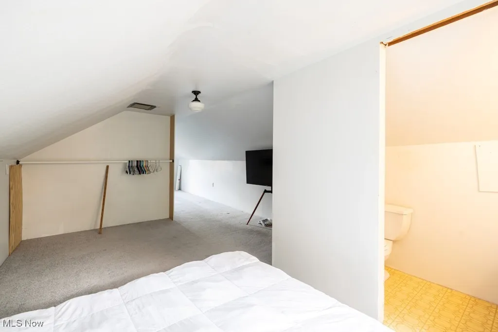 Carpeted bedroom featuring vaulted ceiling