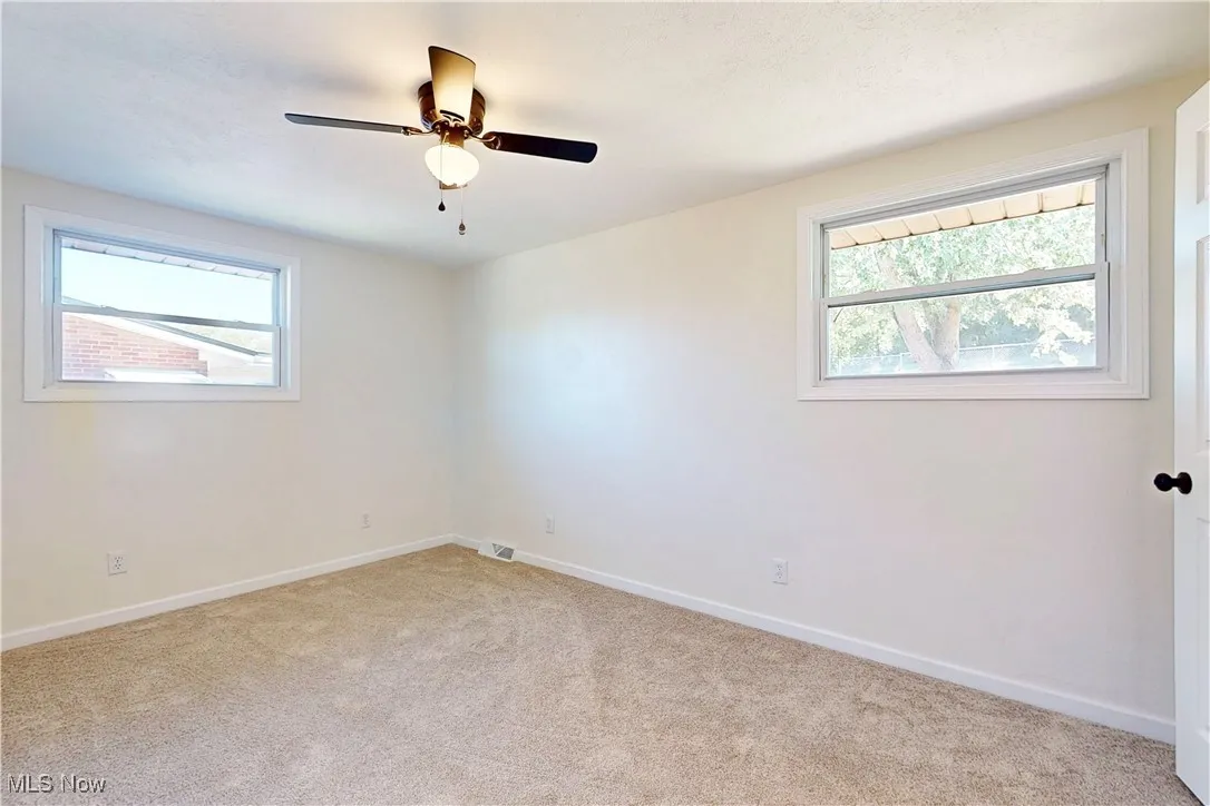 Empty room with healthy amount of natural light and light carpet