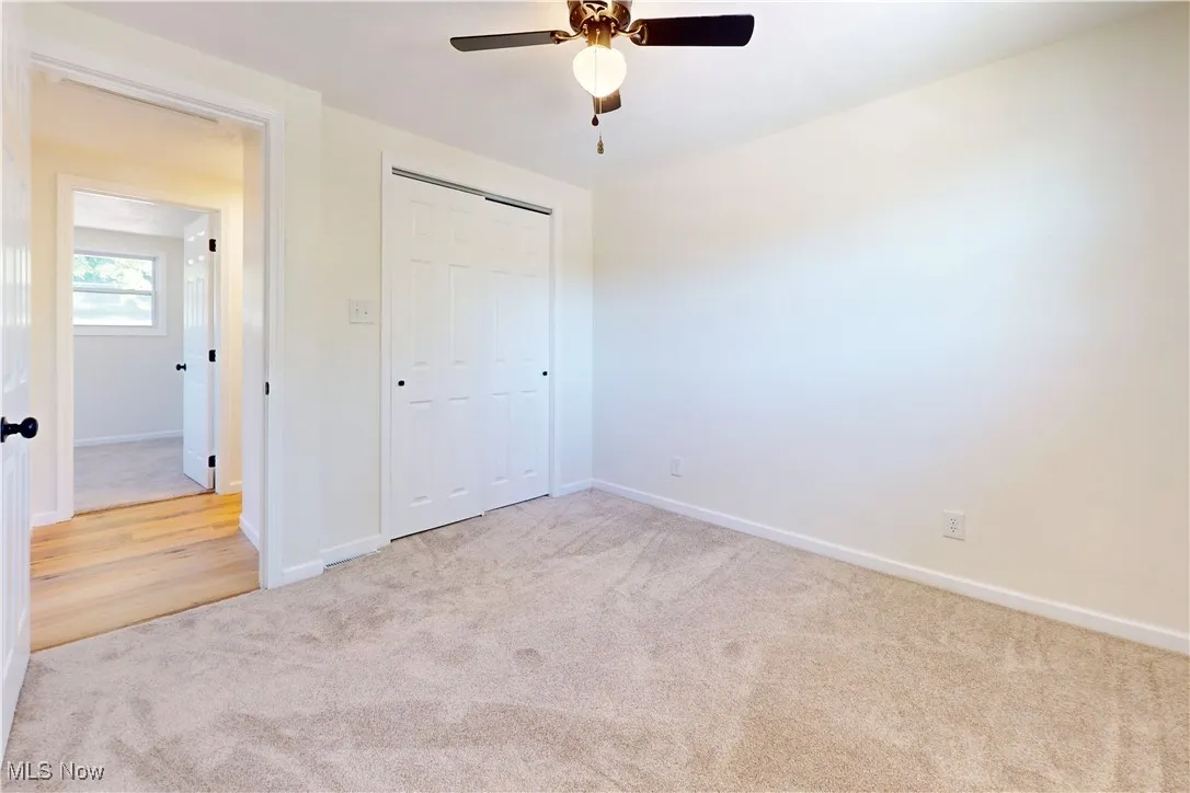 Unfurnished bedroom with light carpet, a closet, and a ceiling fan