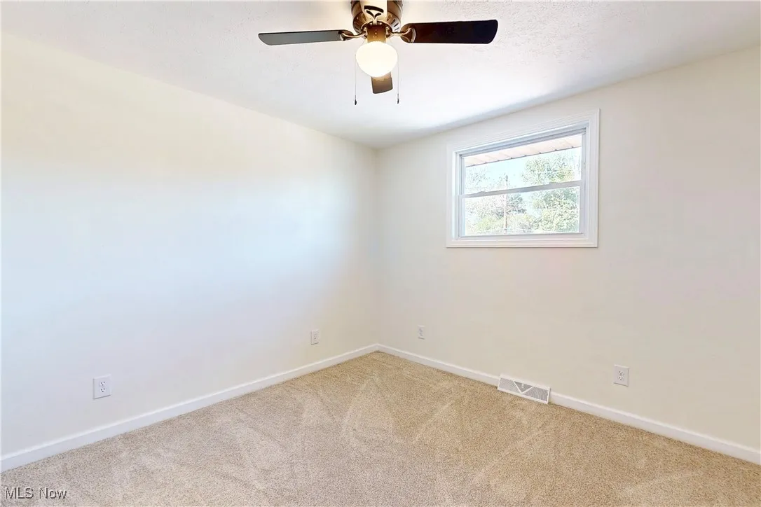 Carpeted spare room featuring baseboards and a ceiling fan