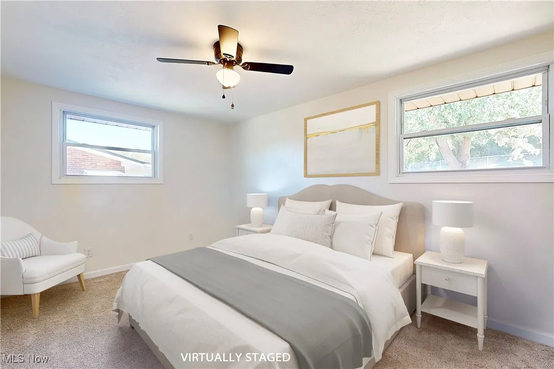 Bedroom featuring light carpet, multiple windows, and a ceiling fan