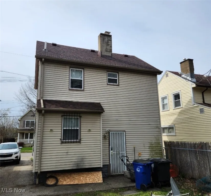 Rear view of house featuring a chimney and a shingled roof