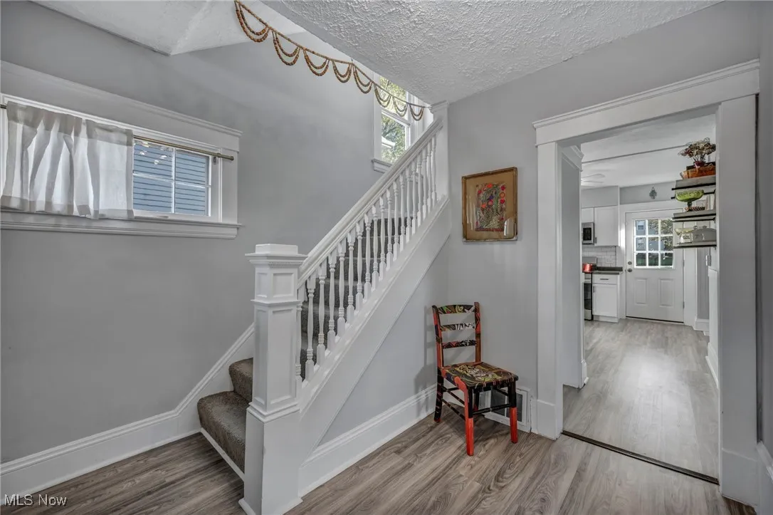 Stairway with wood finished floors and a textured ceiling