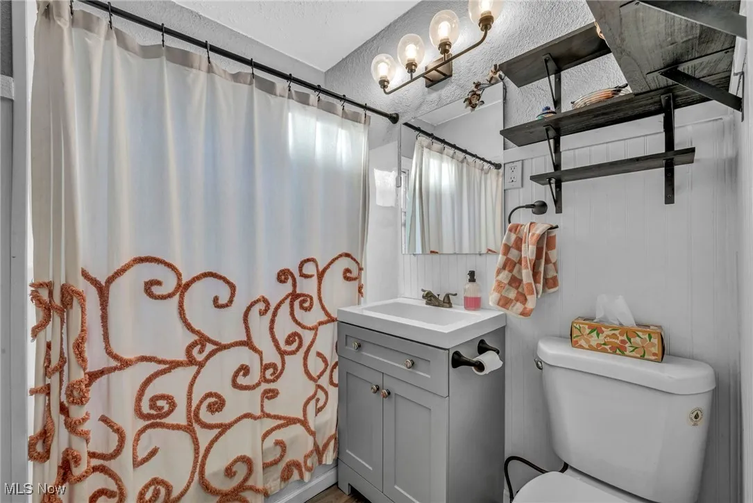 Bathroom with curtained shower, vanity, and a textured ceiling