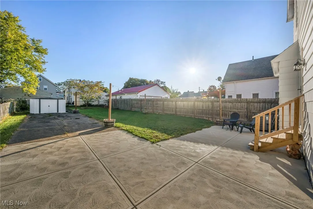 Fenced backyard featuring a patio area and a storage unit
