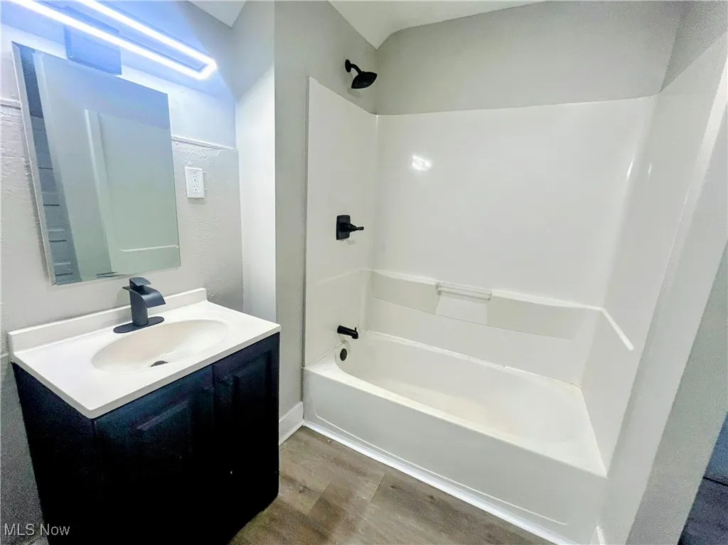 Full bath with wood finished floors, vanity, and  shower combination