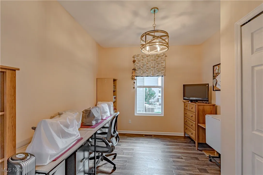 Office space with wood finished floors and a chandelier