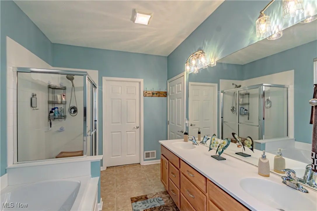 Bathroom featuring a garden tub, double vanity, and a stall shower