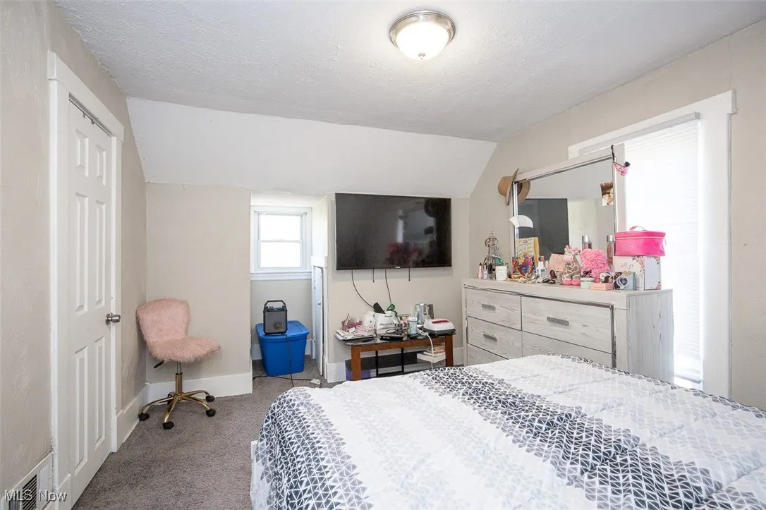 Bedroom featuring light carpet, a textured ceiling, and lofted ceiling