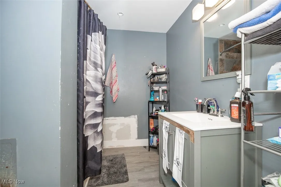 Bathroom featuring vanity, a shower with shower curtain, and light wood-style flooring
