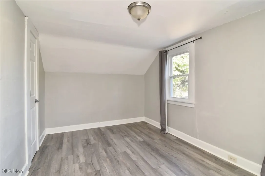 Bonus room with light wood-style flooring and lofted ceiling