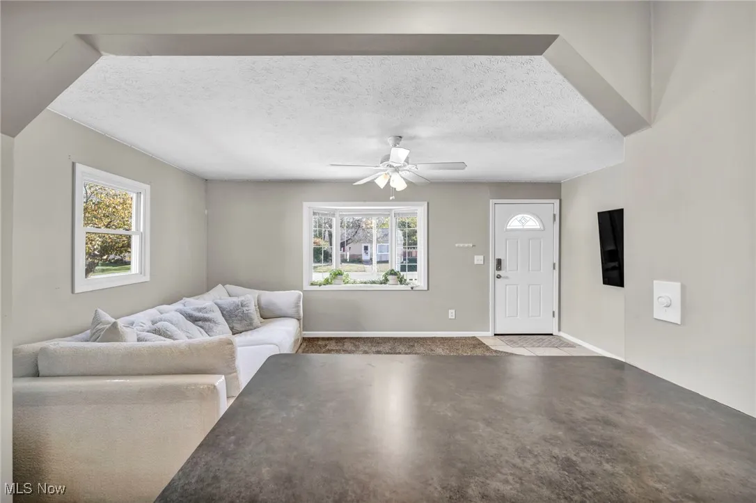 Living room featuring a textured ceiling, a ceiling fan, and finished concrete flooring