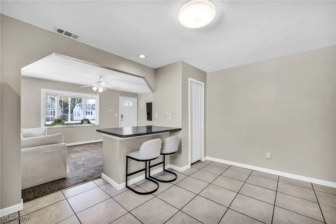 Kitchen featuring a breakfast bar area, a peninsula, open floor plan, dark countertops, and ceiling fan