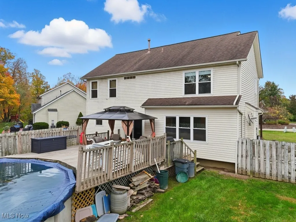 Back of house with a fenced backyard, a gazebo, a wooden deck, and roof with shingles