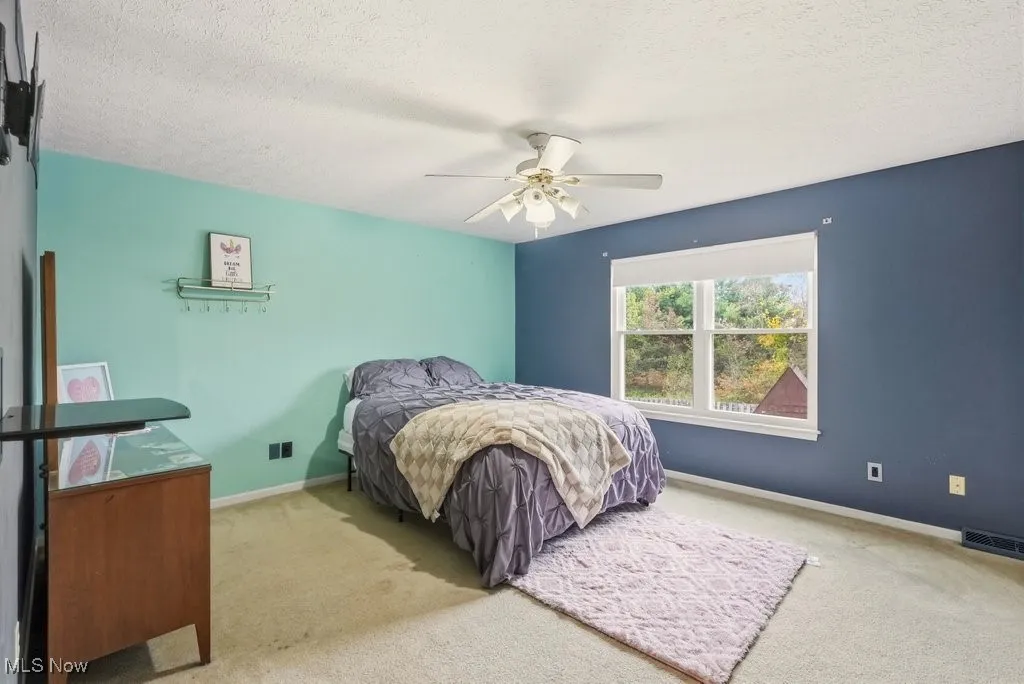 Carpeted bedroom featuring a textured ceiling and ceiling fan