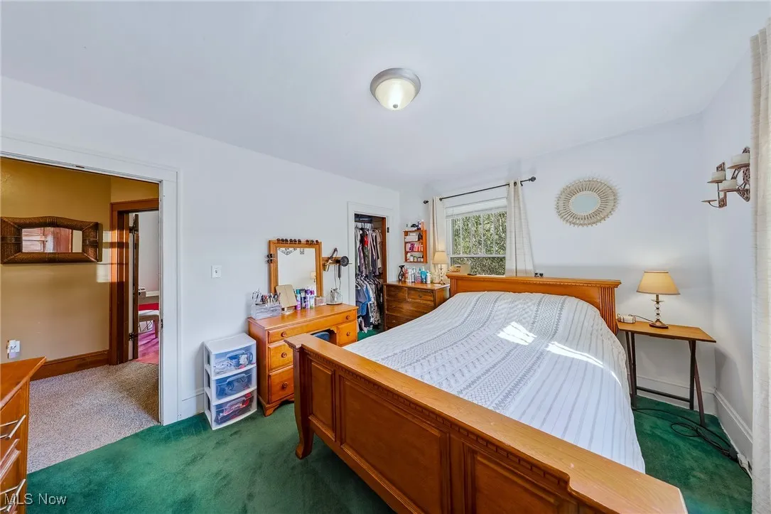 Bedroom with dark colored carpet and a walk in closet