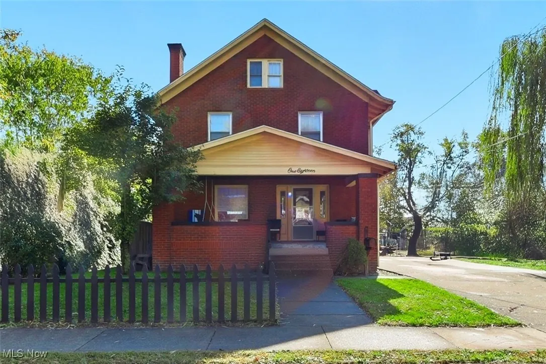 View of front of property featuring covered porch, brick siding, and a chimney