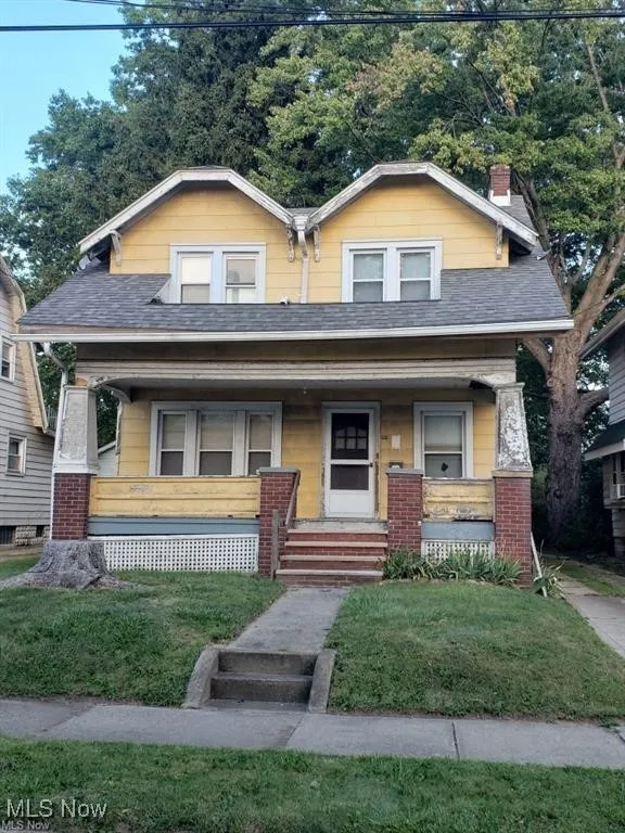 Bungalow-style home with a shingled roof, a porch, a front lawn, and a chimney