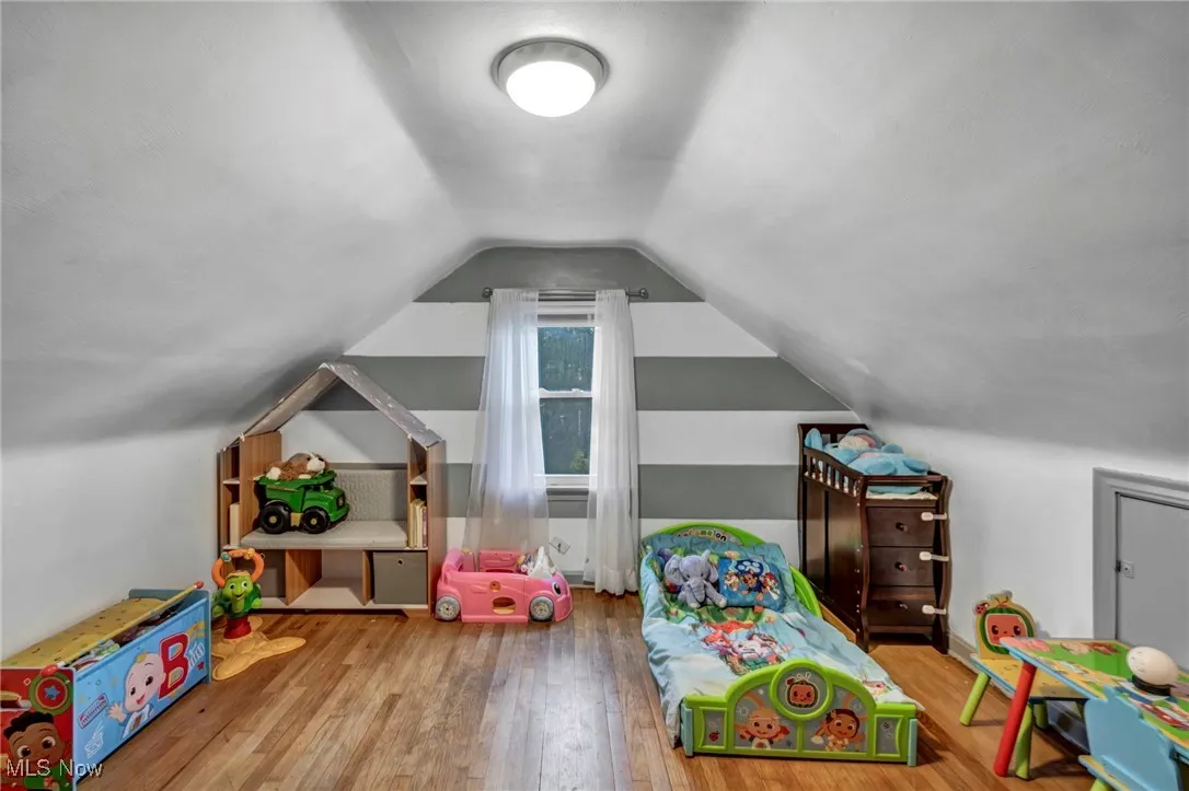 Recreation room with wood finished floors and vaulted ceiling
