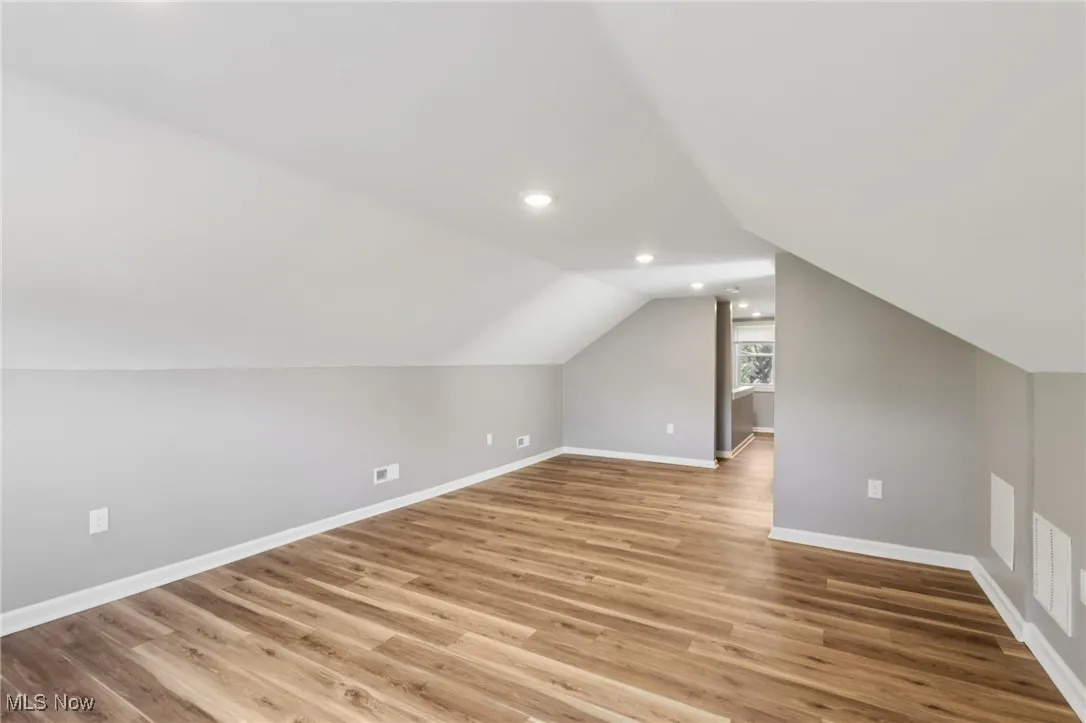 Additional living space with light wood-style flooring, vaulted ceiling, and recessed lighting