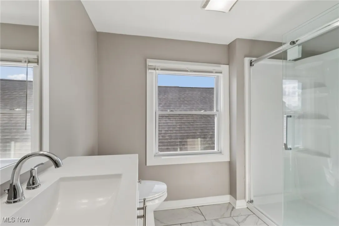 Bathroom featuring light marble finish floors, a stall shower, and vanity