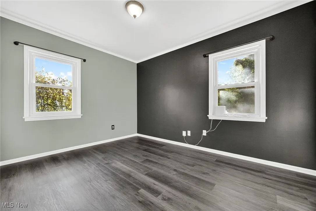 Empty room with dark wood-type flooring and crown molding