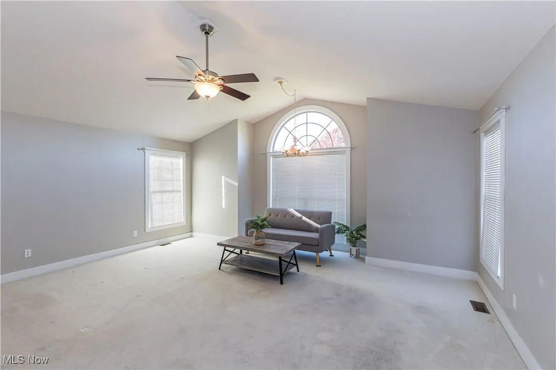 Living area with carpet flooring, lofted ceiling, and ceiling fan