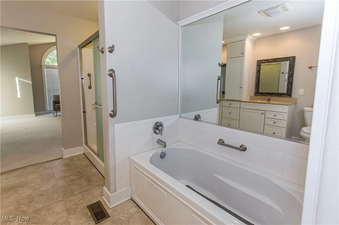Bathroom featuring a bath, a shower stall, and vanity