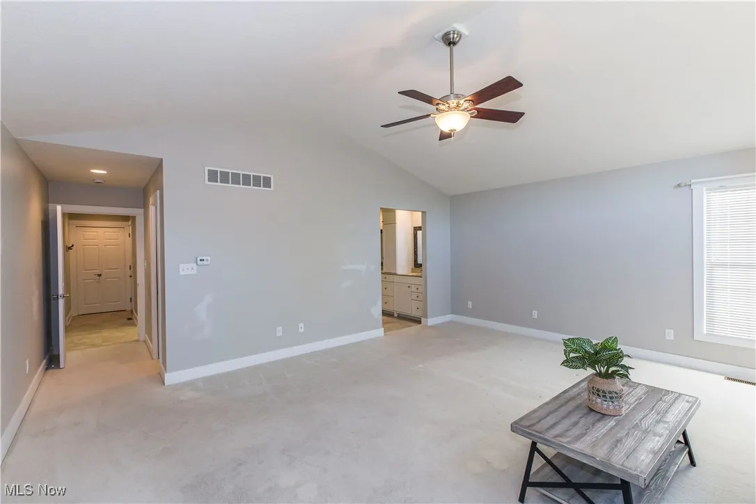 Unfurnished living room with light colored carpet, lofted ceiling, and a ceiling fan