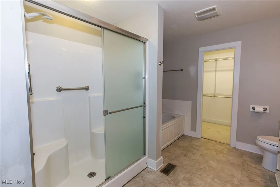 Full bath with a spacious closet, a shower stall, and a garden tub