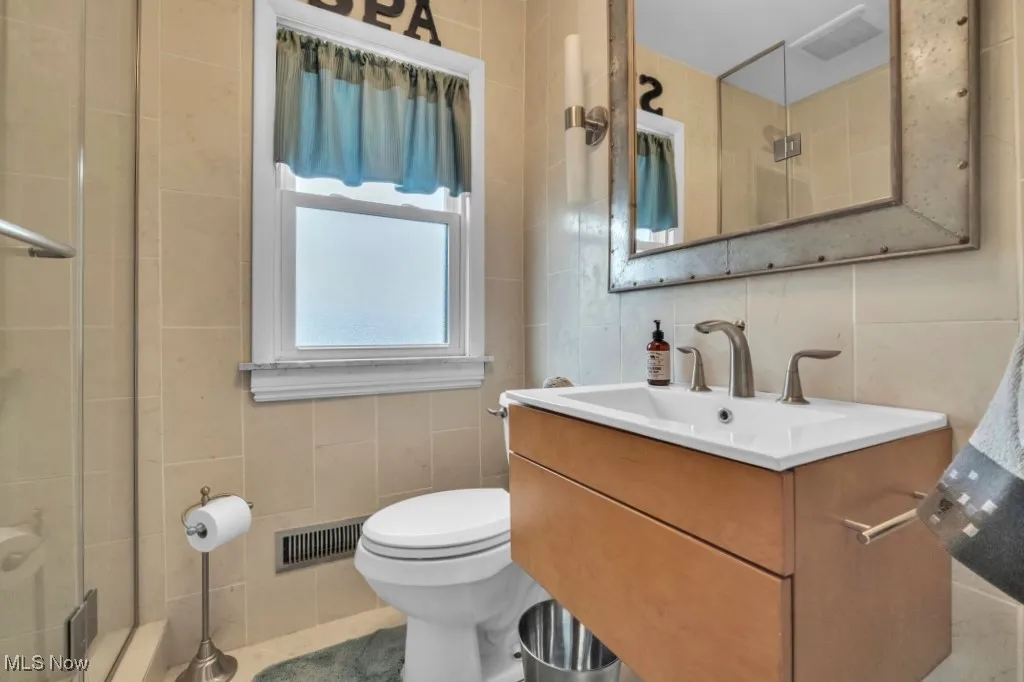 Bathroom featuring tile walls, vanity, and tiled shower