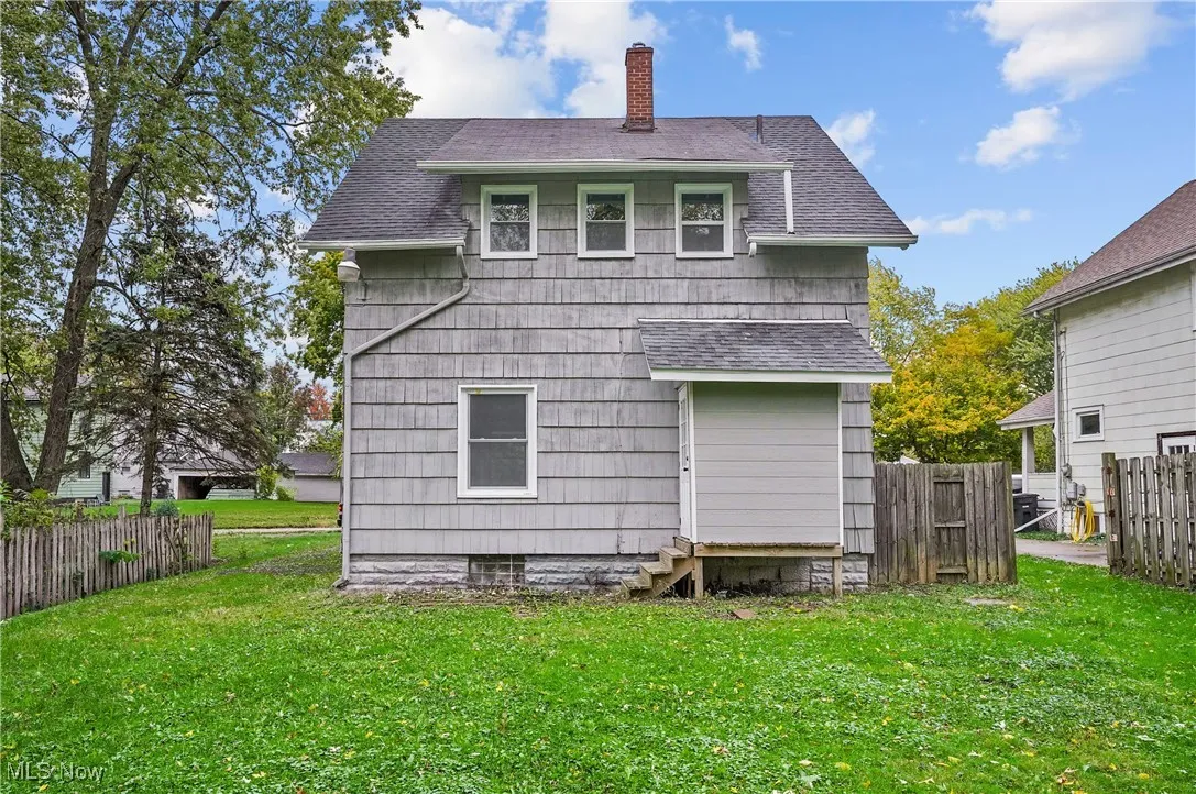 Back of house with a shingled roof, a chimney, and entry steps