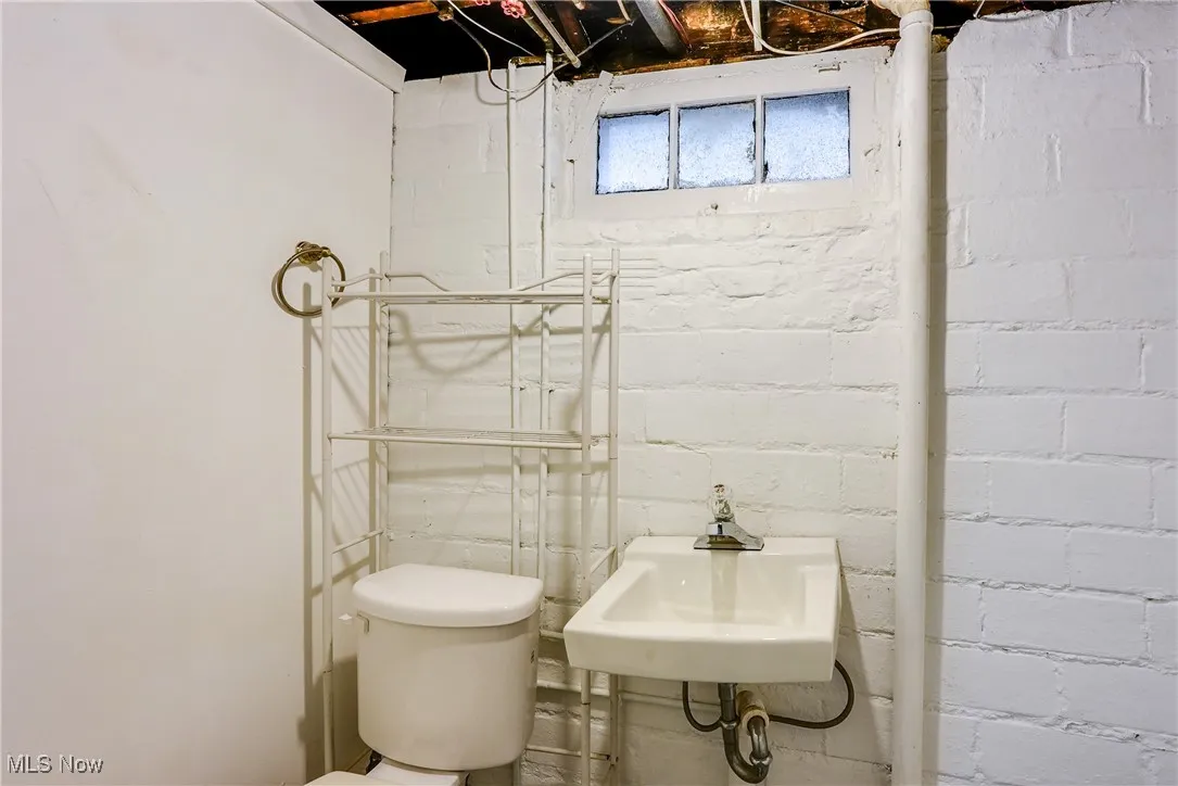 1/2 Bathroom with toilet and a sink in the basement.