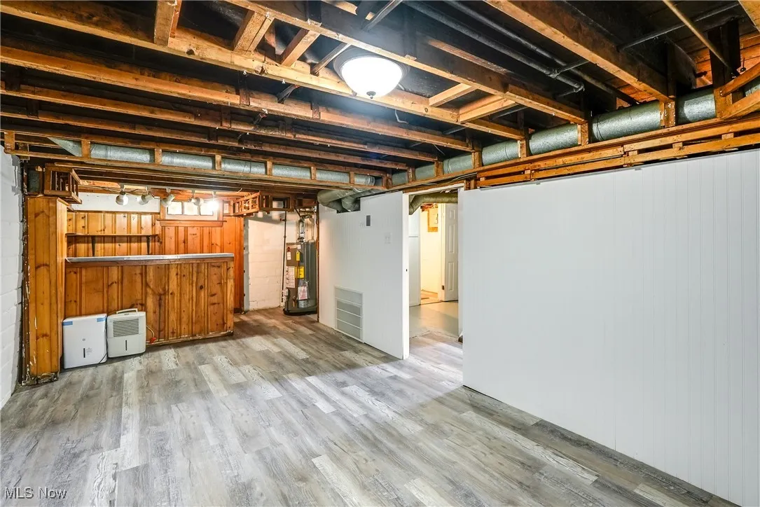 Basement featuring dry bar, light vinyl flooring, and updated water heater