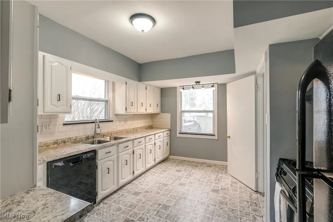 Kitchen with backsplash, black appliances, light countertops, and white cabinets.  All kitchen appliances remain.