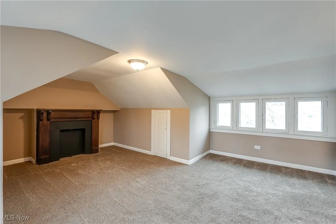 Additional living space on the third floor with storage, character windows, faux fireplace, and light-colored carpet.