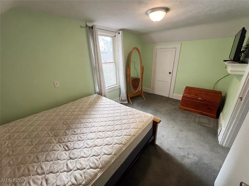 Carpeted bedroom featuring a textured ceiling and baseboards