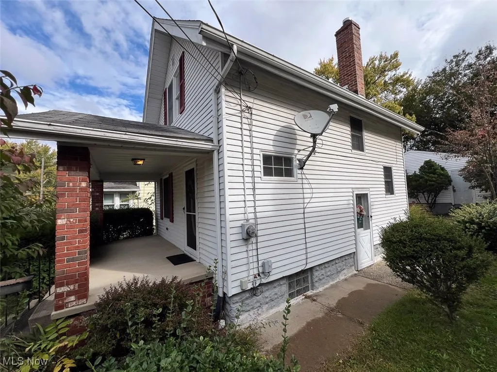 View of home's exterior featuring a chimney and covered porch