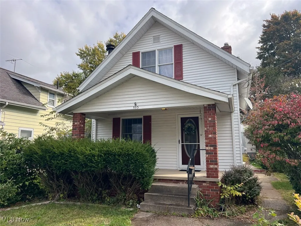 Bungalow featuring covered porch, a chimney, and brick siding