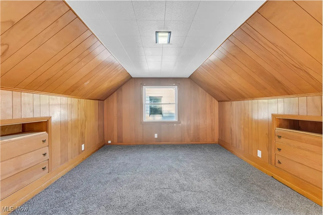 Bonus room with wood walls, vaulted ceiling, wooden ceiling, and light carpet
