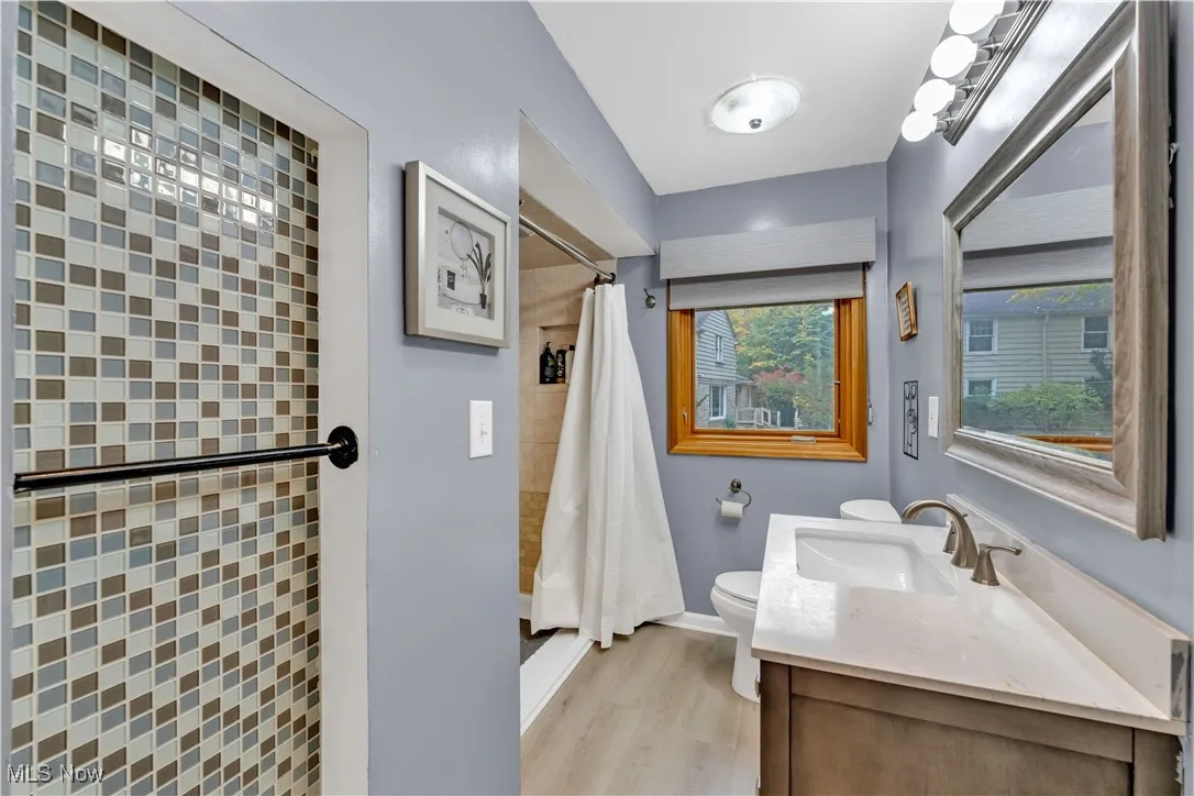 Bathroom featuring vanity, tiled shower, and light wood-style floors