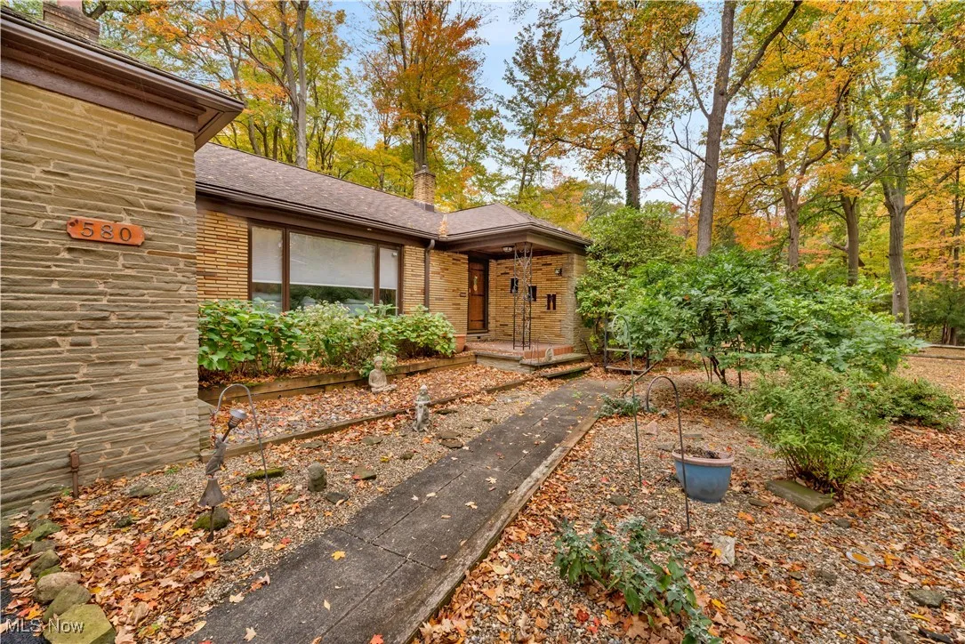 Entrance to property with brick siding, a shingled roof, and a porch