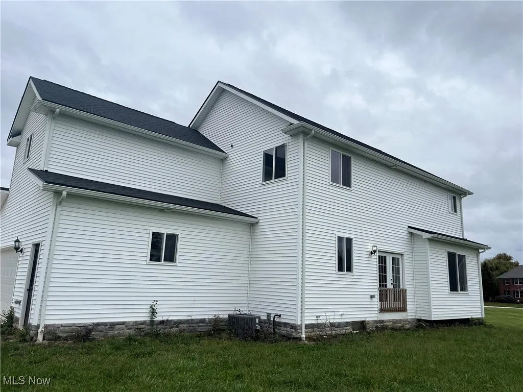Rear view of property featuring a garage, a lawn, and french doors