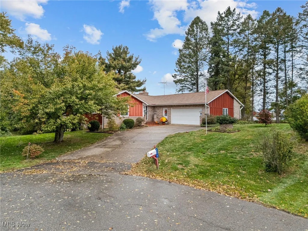 View of front facade with a front yard, board and batten siding, asphalt driveway, and a garage