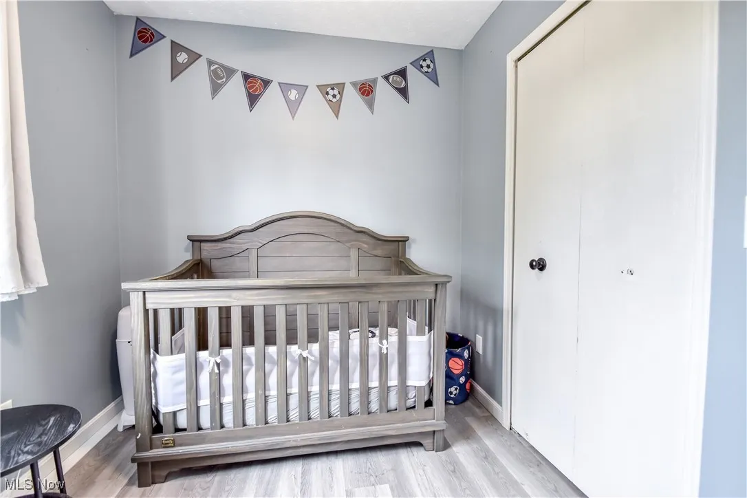 Bedroom with wood finished floors, a crib, and a closet