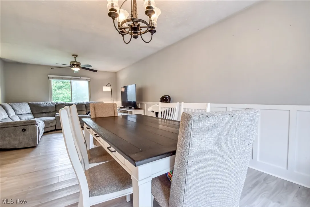 Dining space featuring light wood-type flooring, a chandelier, and a ceiling fan