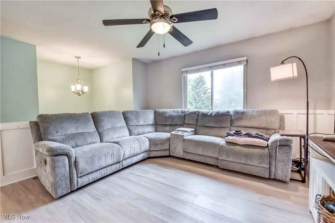 Living room with light wood finished floors, a chandelier, and a ceiling fan