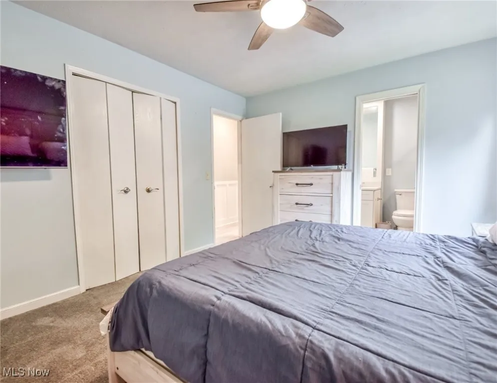 Bedroom with carpet floors, a closet, a ceiling fan, and ensuite bath
