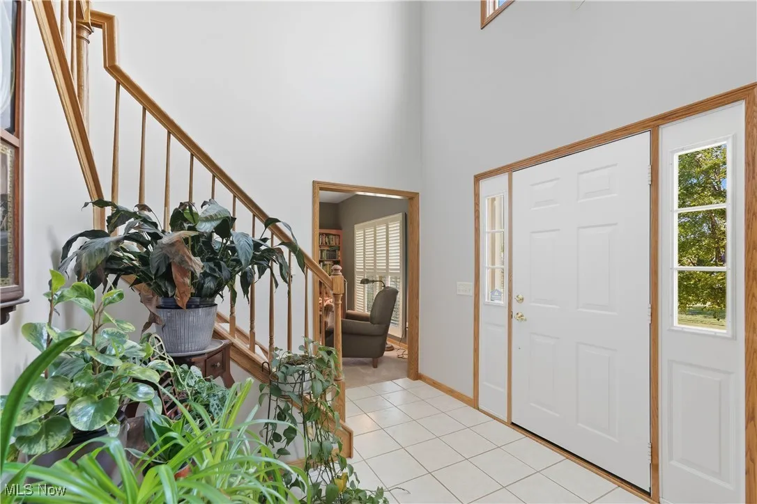 Foyer entrance featuring light tile patterned flooring, stairway, and a towering ceiling