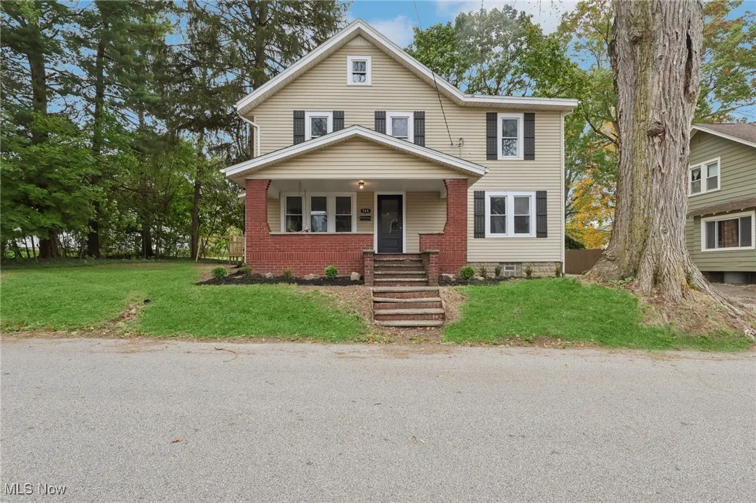 View of front of property featuring covered porch and a front yard